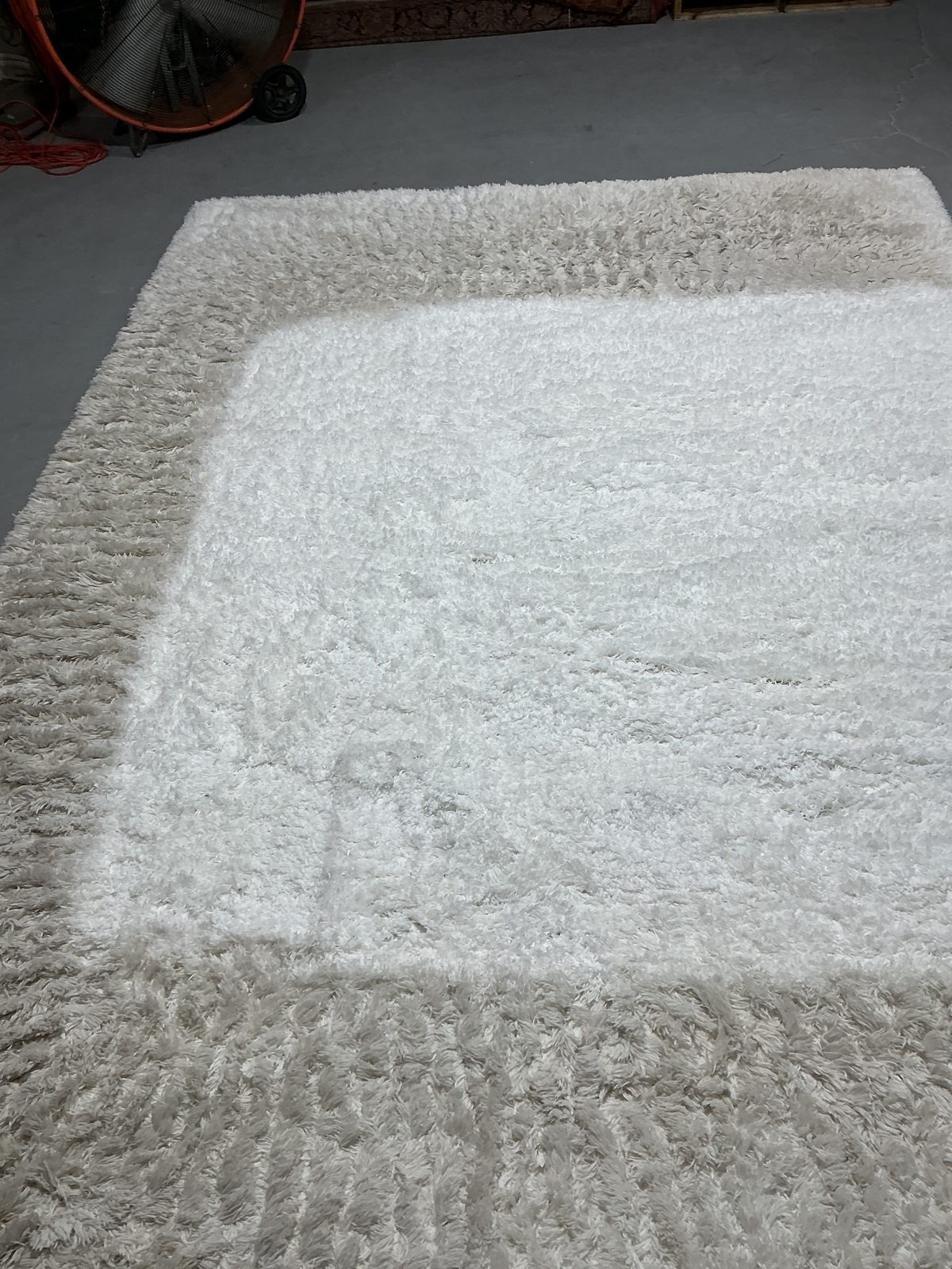 White shag rug with gray soiled border and clean center where furniture sat, before cleaning